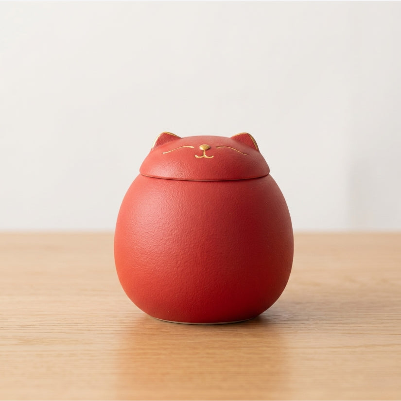 Red cat-shaped container on a wooden surface with a light gray background lucky cat, maneki-neko, ceramic tea canister, Japanese kitchen decor, loose leaf tea storage, good luck gift, Asian home decor